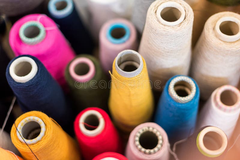 Vue d'arrière-plan de différents fils de cachemire de couleur. Vue d'arrière-plan en grand angle de différents fils de cachemire de couleur sur des bobines coniques dans une usine de tricot avec mise au point à une bobine jaune au centre