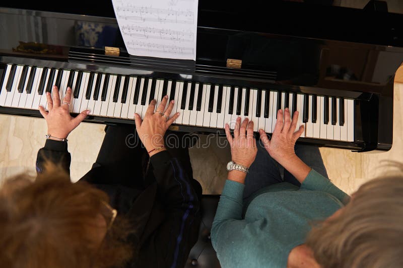 Vue d'en haut de deux pianistes femmes jouant du piano à quatre mains étudiant une nouvelle composition musicale. leçon de musique photo libre de droits