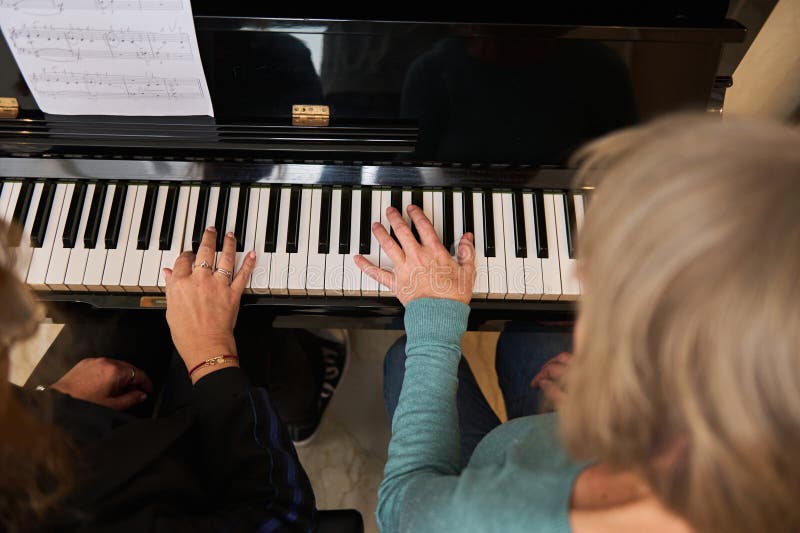 Vue d'en haut deux femmes multi-ethniques matures jouant du piano à quatre mains et orgue dans le studio familial images stock