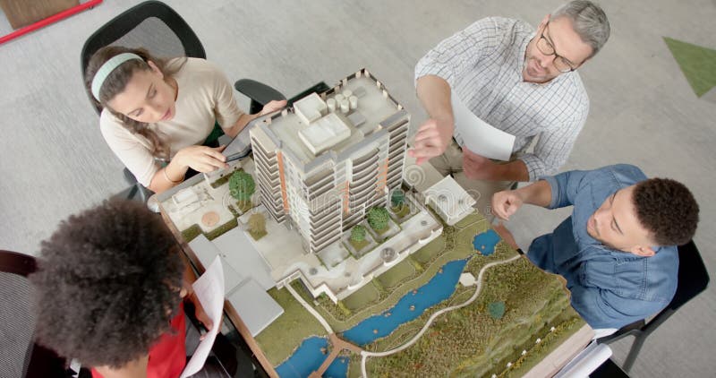 Vue d'ensemble d'une équipe d'ingénieurs divers discutant d'un modèle de bâtiment 3d au bureau banque de vidéos