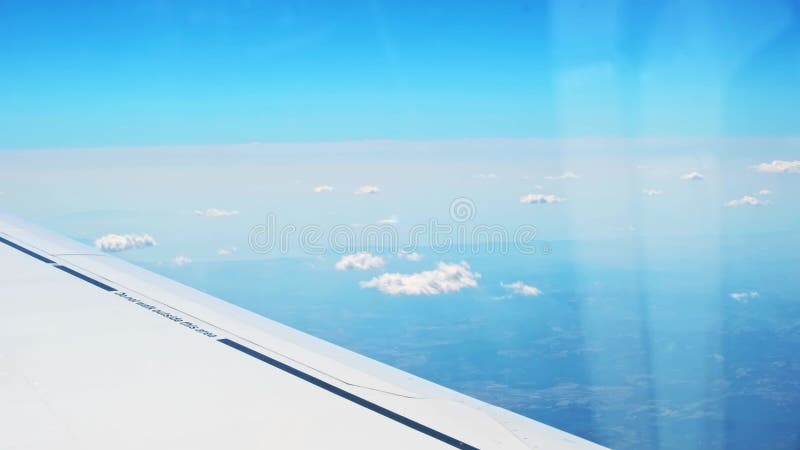 Vue d'une aile d'avion d'un hublot sur fond bleu ciel. un avion de transport vole au-dessus des nuages dans banque de vidéos