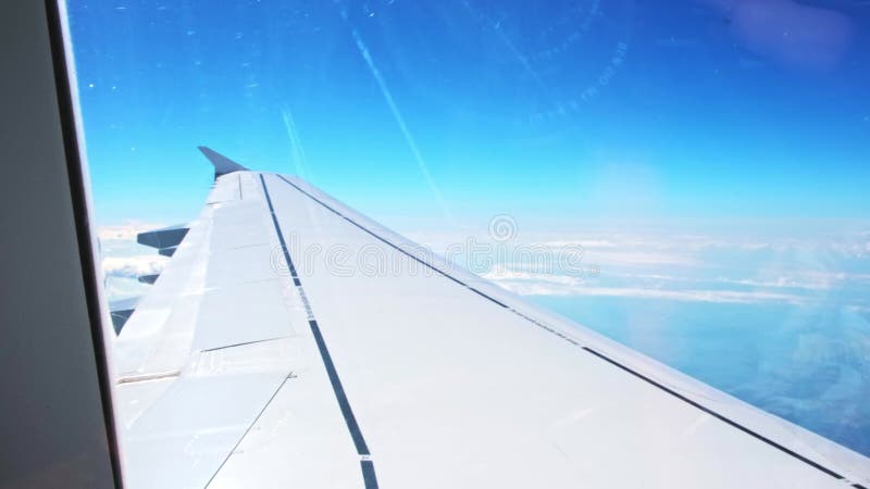 Vue d'une aile d'avion d'un hublot sur fond bleu ciel. un avion de transport vole au-dessus des nuages dans banque de vidéos