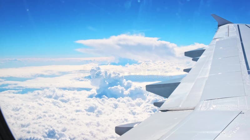 Vue d'une aile d'avion d'un hublot sur fond bleu ciel. un avion de transport vole au-dessus des nuages dans banque de vidéos