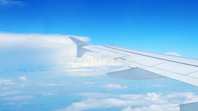 Vue d'une aile d'avion d'un hublot sur fond bleu ciel. un avion de transport vole au-dessus des nuages dans clips vidéos