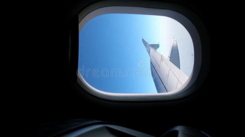 Vue d'une aile d'avion d'un hublot sur fond bleu ciel. un avion de transport vole au-dessus des nuages dans clips vidéos