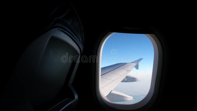 Vue d'une aile d'avion d'un hublot sur fond bleu ciel. un avion de transport vole au-dessus des nuages dans clips vidéos