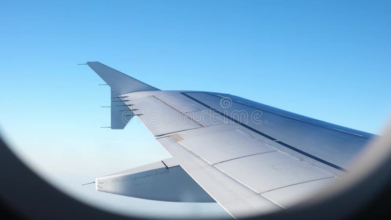 Vue d'une aile d'avion d'un hublot sur fond bleu ciel. un avion de transport vole au-dessus des nuages dans banque de vidéos