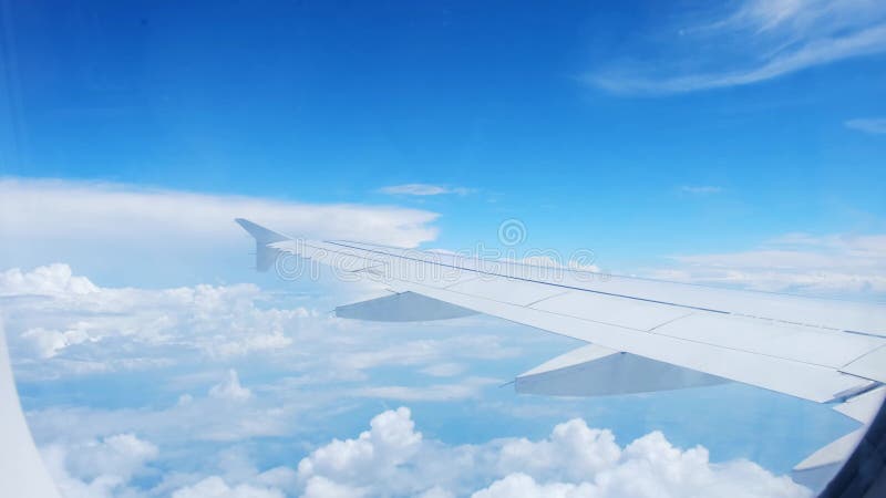Vue d'une aile d'avion d'un hublot sur fond bleu ciel. un avion de transport vole au-dessus des nuages dans clips vidéos