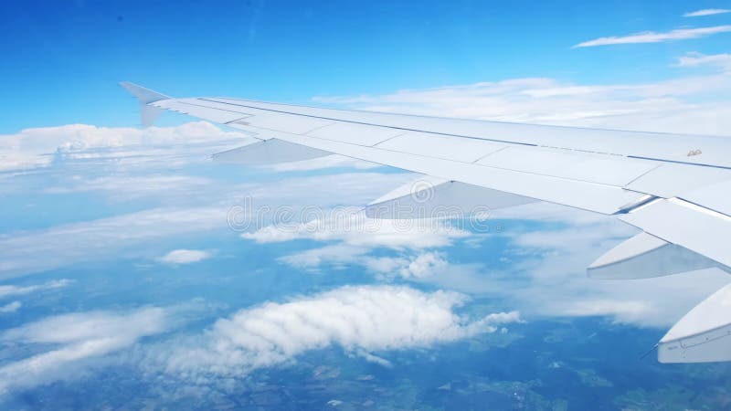 Vue d'une aile d'avion d'un hublot sur fond bleu ciel. un avion de transport vole au-dessus des nuages dans clips vidéos
