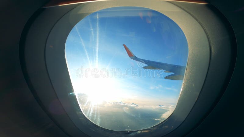 Vue d'une fenêtre d'avions avec le soleil et l'aile plate