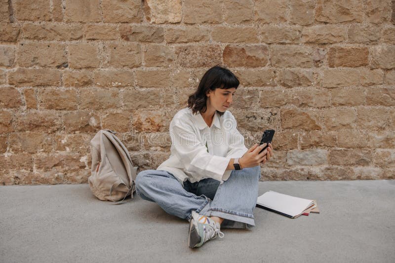 Vue d'une jolie femme brune regardant le téléphone et bavardant photos stock