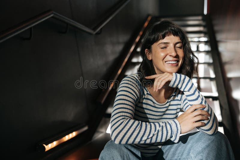 Vue d'une jolie jeune femme assise et souriante de près image stock