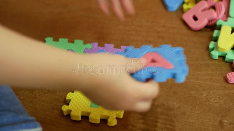 Vue de closeup d'un tout-petit jouant des lettres de puzzle en mousse colorée et des chiffres éducation jouets clips vidéos