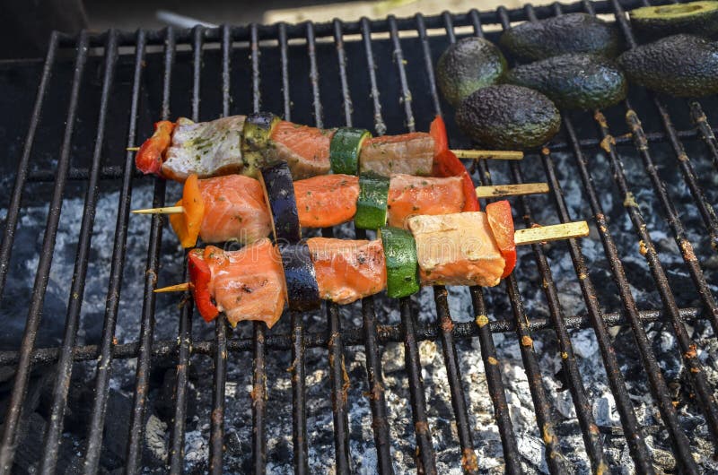 Vue de closeup de deux brochettes avec des morceaux d'apéritif de courgettes de saumon et poivrons sur un barbecue grill photographie stock