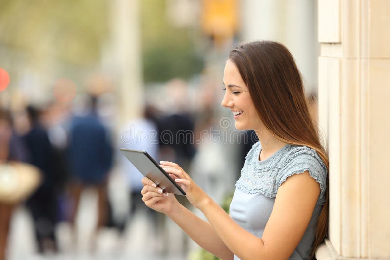 Vue de côté d'une fille à l'aide d'un comprimé sur la rue images libres de droits Vue de côté d'une fille à l'aide d'un comprimé sur la rue images libres de droits