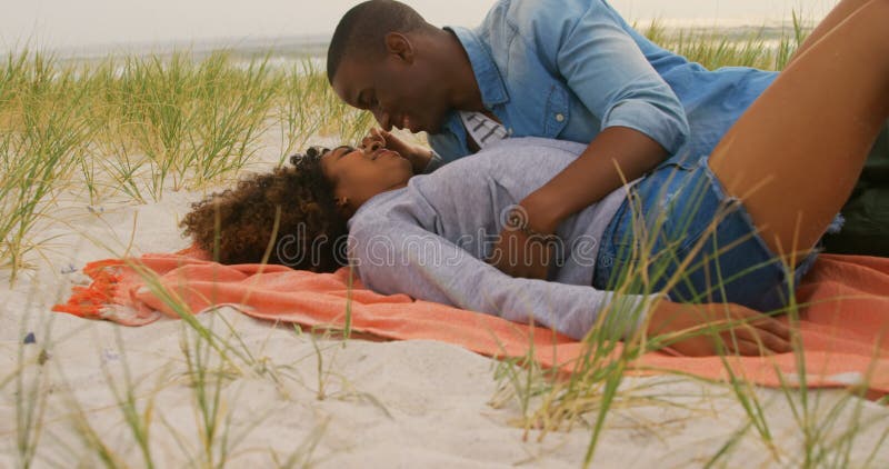Vue de côté des couples d'Afro-américain ayant l'amusement sur la plage 4k banque de vidéos