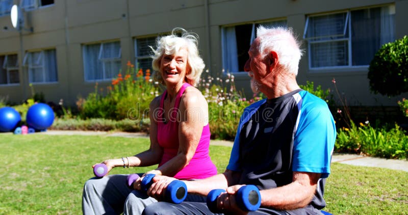 Vue de côté des couples supérieurs caucasiens s'exerçant avec des haltères dans le jardin de la maison de repos 4k banque de vidéos