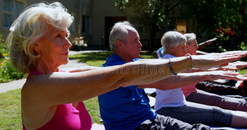 Vue de côté des personnes supérieures de métis actif exécutant le yoga dans le jardin de la maison de repos 4k clips vidéos