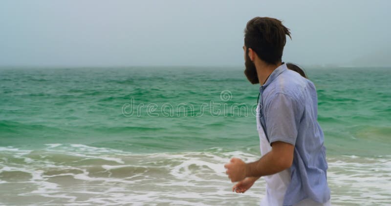 Vue de côté du fonctionnement caucasien de couples avec de pair dessus la plage 4k clips vidéos