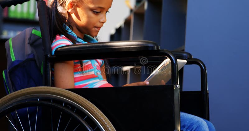 Vue de côté de l'écolière handicapée d'Afro-américain lisant un livre dans la bibliothèque à l'école 4k banque de vidéos