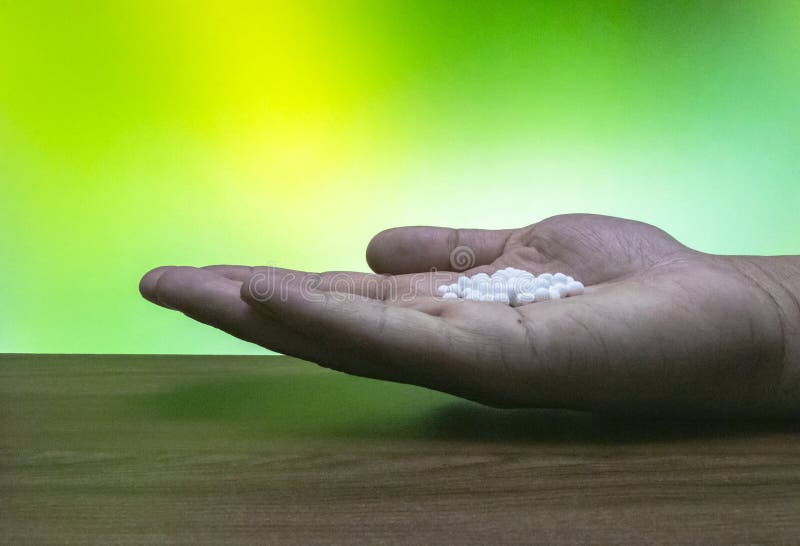 Vue de côté de la paume de la main de l'homme contenant les pilules homéopathiques image libre de droits Vue de côté de la paume de la main de l'homme contenant les pilules homéopathiques image libre de droits
