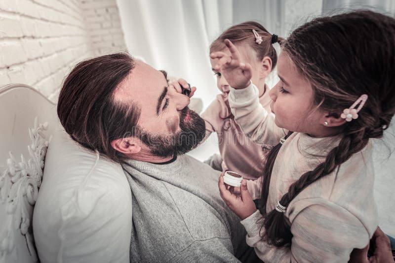 Vue de côté de la peinture de filles que leurs pères font face avec composent photos stock Vue de côté de la peinture de filles que leurs pères font face avec composent photos stock