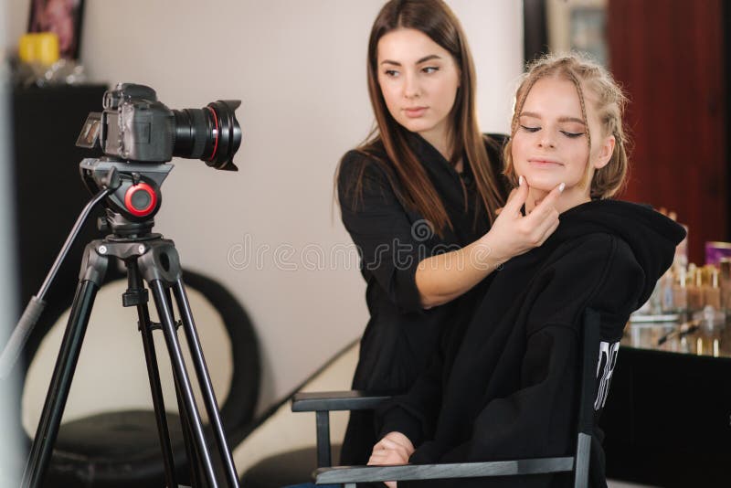 Vue de côté de maquillage artiste travail avec beau modèle blond cheveux en studio jusqu'à ce que les films de la caméra processus de maquillage. blog de maquilleur.