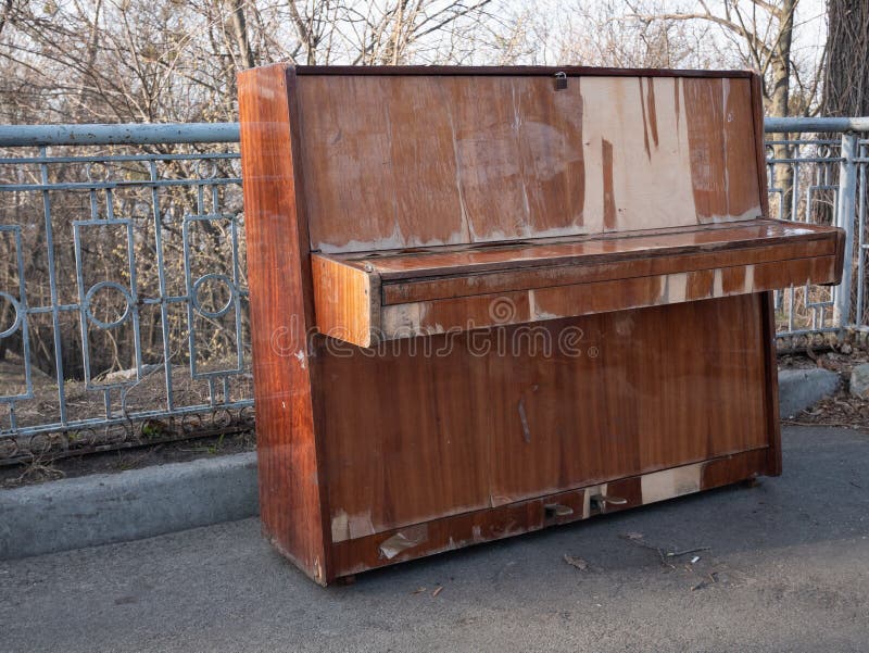 Vue de c?t? sur le r?tro piano en bois classique abandonn? au parc de ville concept de concert d'air ouvert photographie stock libre de droits Vue de c?t? sur le r?tro piano en bois classique abandonn? au parc de ville concept de concert d'air ouvert photographie stock libre de droits
