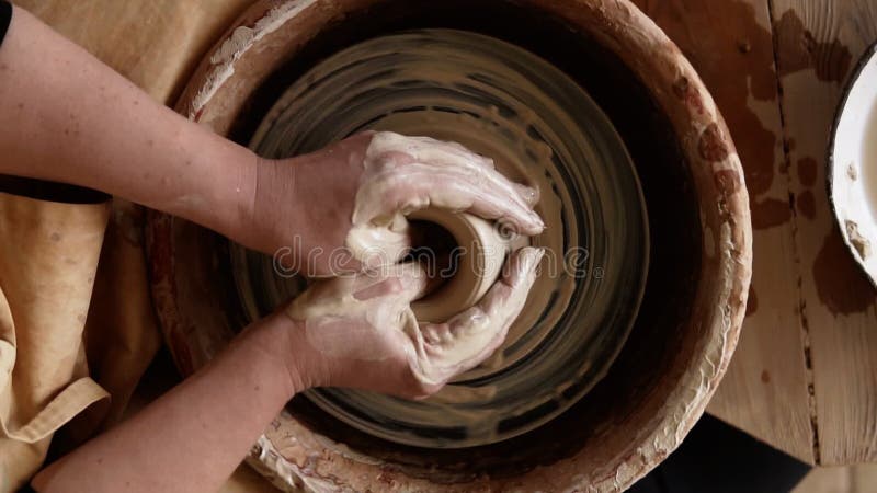 Vue de dessus de gros plan des mains de potiers avec le travail avec de l'argile humide sur une roue de poterie faisant un produit clips vidéos