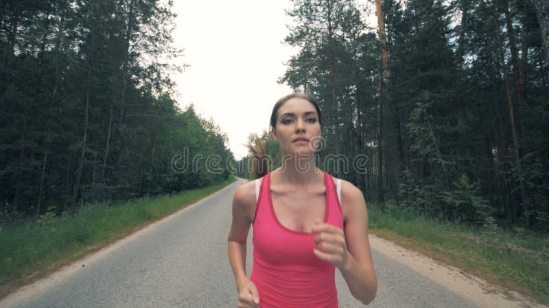 Vue de face d'une jeune femme tout en courant dans le mouvement lent banque de vidéos