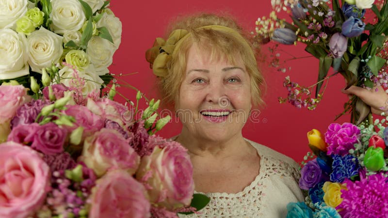 Vue de face de la femme supérieure enthousiaste souriant près de fleurs