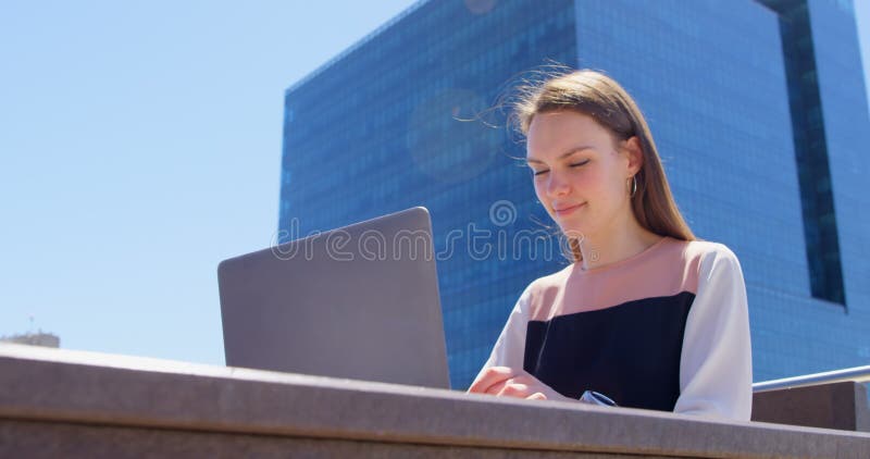 Vue de face de la jeune femme d'affaires caucasienne fra? che travaillant sur l'ordinateur portable dans le balcon du bureau moder banque de vidéos