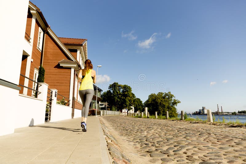 Vue de jeune femme fonctionnant sur le trottoir dans le matin Concept conscient de santé image libre de droits Vue de jeune femme fonctionnant sur le trottoir dans le matin Concept conscient de santé image libre de droits