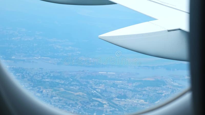 Vue de l'aile de l'aéronef depuis la cabine de l'aéronef à travers le hublot. L'avion décolle sur la ville. Nuageux banque de vidéos