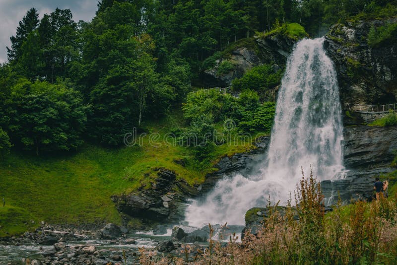 Vue de la cascade steinsdalsfossen dans une vallée émergeant de la forêt de la région de bergen images libres de droits