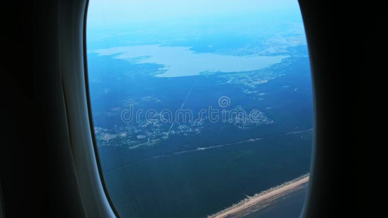 Vue depuis la fenêtre avec l'aile de l'avion. Avion approchant de présenter des vawes d'eau bleue zones forestières vertes et long banque de vidéos