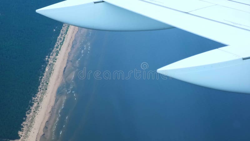 Vue depuis la fenêtre avec l'aile de l'avion. Avion approchant de présenter des vawes d'eau bleue zones forestières vertes et long banque de vidéos