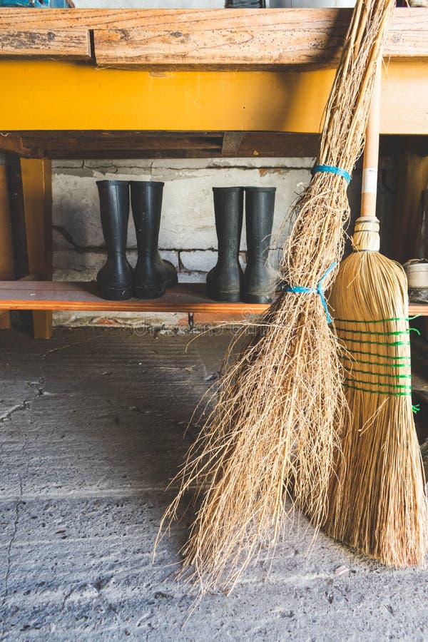 Vue des balais et deux paires de bottes en caoutchouc sous une table dedans dans une salle d'entreposage photo libre de droits Vue des balais et deux paires de bottes en caoutchouc sous une table dedans dans une salle d'entreposage photo libre de droits