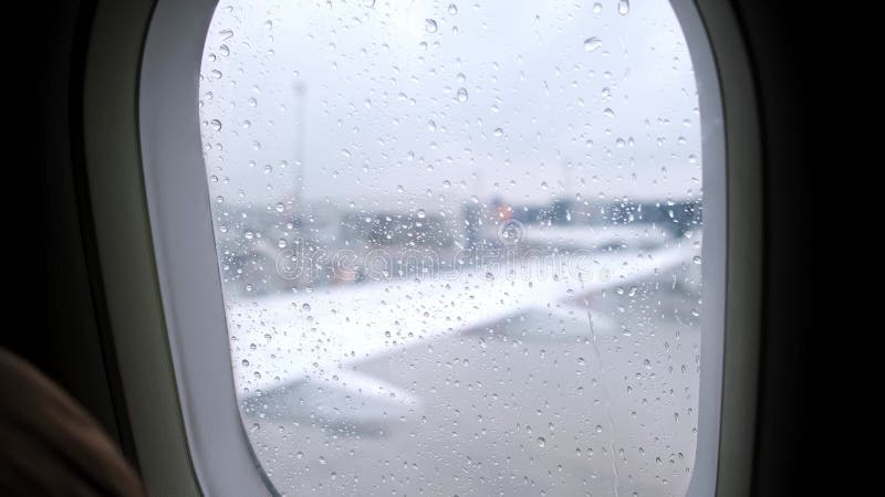 Vue des gouttes d'eau qui descendent dans une fenêtre d'avion. temps pluvieux. les passagers attendent le départ dans la cabine de banque de vidéos