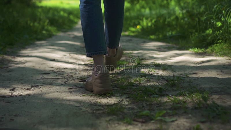 Vue des jambes de la jeune femme en marchant sur le chemin dans la forêt sur le spbd de jour d'été.