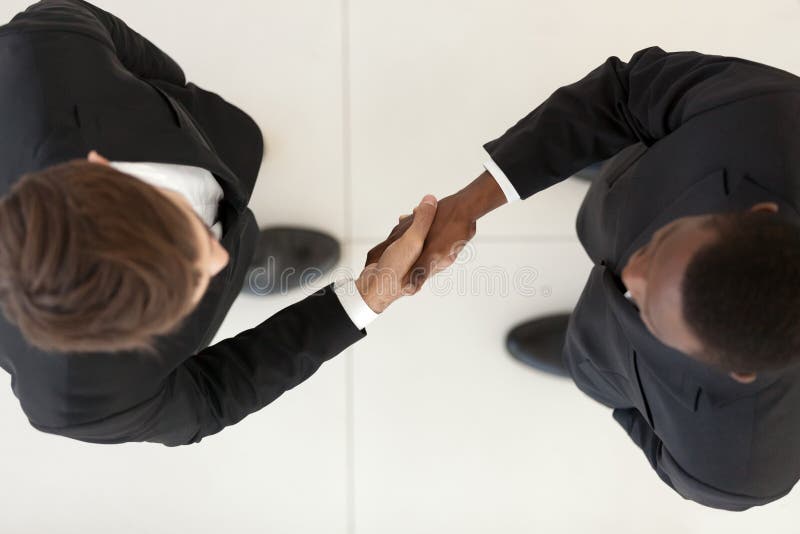 Vue directement en haut des hommes d'affaires divers dans les costumes se serrant la main image libre de droits Vue directement en haut des hommes d'affaires divers dans les costumes se serrant la main image libre de droits