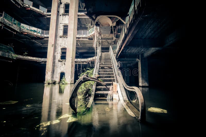 Dramatic view of damaged escalators in abandoned shopping mall sunken by rain flood waters. Apocalyptic and evil concept. Dramatic view of damaged escalators in abandoned shopping mall sunken by rain flood waters. Apocalyptic and evil concept