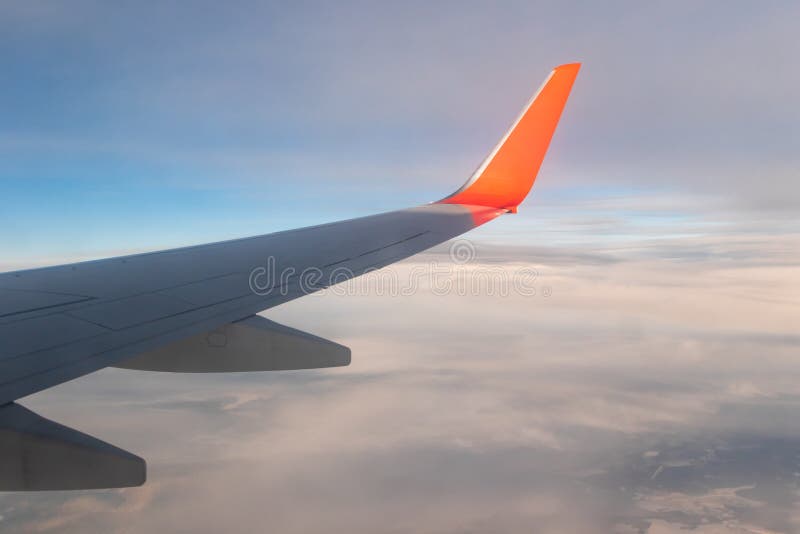 Vue du ciel bleu clair de la hauteur du vol au-dessus des nuages de la fenêtre de l'avion au soleil brillant. partie d'une aile d'avion dans le cadre