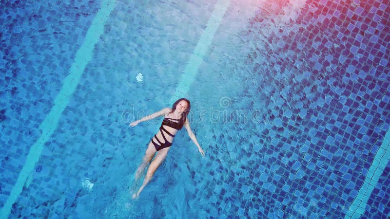 Vue du haut photo aérienne d'un séduisant modèle sexy en maillot de bain noir profite de se détendre dans la piscine de l'hôtel. f banque de vidéos