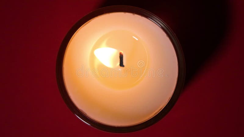 Vue du haut sur la bougie brûler près sur fond rouge foncé. vidéo haute vitesse à ralenti. flamme de bougie près. le banque de vidéos