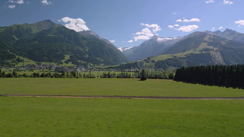 Vue en drone d'une vallée alpine luxuriante avec un village niché entre des sommets vertigineux banque de vidéos