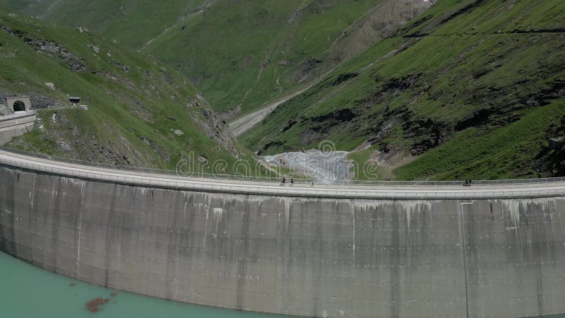Vue en drone du Stausee Mooserboden reflétant les crêtes de montagne et les falaises sous le ciel alpin lumineux banque de vidéos