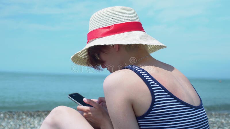 Vue en gros plan de la jeune femme à l'aide du smartphone à disposition au fond d'abrégé sur bord de la mer