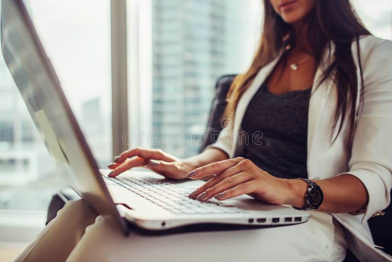 Vue en gros plan du journaliste féminin élégant écrivant un article utilisant le netbook se reposant dans le bureau moderne photographie stock libre de droits Vue en gros plan du journaliste féminin élégant écrivant un article utilisant le netbook se reposant dans le bureau moderne photographie stock libre de droits