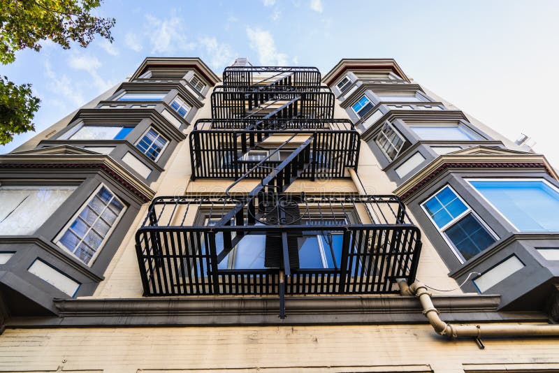 Vue extérieure de l'immeuble résidentiel multifamilial; Les anciens escaliers de secours en métal accrochés au côté du bâtiment ; photo stock Vue extérieure de l'immeuble résidentiel multifamilial; Les anciens escaliers de secours en métal accrochés au côté du bâtiment ; photo stock